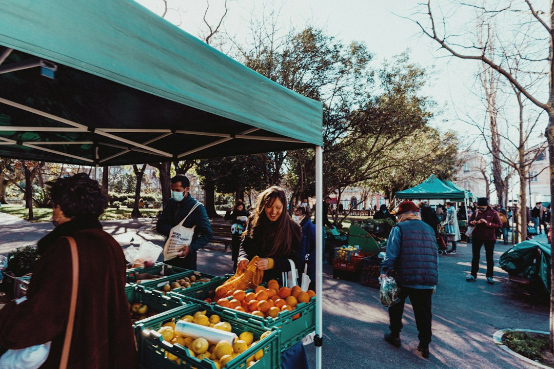 a group of people standing around a fruit stand