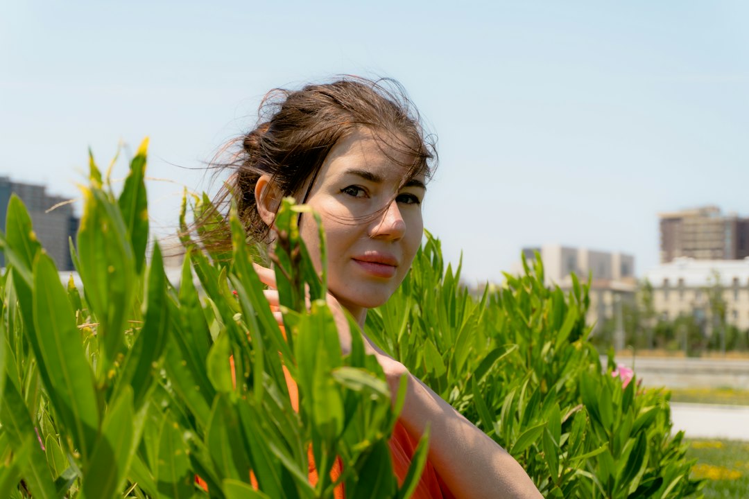 Young woman peeking through green plants outdoors